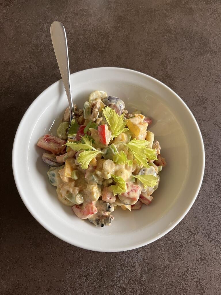 White Bowl of coronation salad with metal spoon on granite worktop